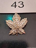Front view of silver-tone rhinestone maple leaf brooch