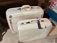 Two off-white Samsonite suitcases, large and small sizes