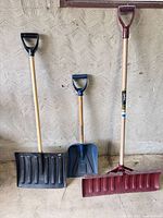 Front view of three snow shovels standing upright