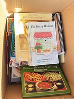 Box containing several cookbooks with The Best of Bethany and Betty Crocker Money-Saving Dinners visible