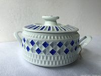 Lidded porcelain bowl showing side profile, handles and geometric pattern