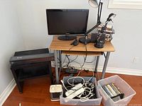 Overall view showing desk, monitor, lamp, DVDs, side stand and bins of cables and discs