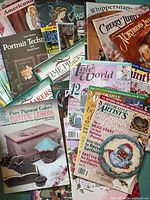 Stack of assorted decorative painting books, magazines, Santa ornament