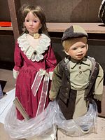 Both porcelain dolls on stands showing full outfits and scale