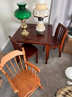 Table with two dark chairs and light wood rocking chair visible; lamps atop table not included