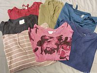 Seven folded sweaters and sweatshirts in various colors