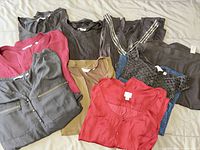Nine tops laid out showing variety of styles and colours