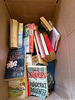 Open box showing multiple paperback books including Debbie Macomber and Iris Johansen titles