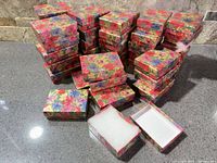 Stacks of multicolor floral pattern jewelry boxes, some open showing white cotton inserts