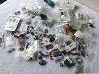 Overview of assorted bead bags, findings, pendants spread on white cloth