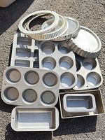 Group of assorted metal baking pans including tart, muffin, loaf and bar pans