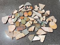 Spread of assorted stone slab offcuts and discs on dark surface