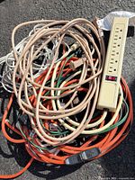 All cords coiled together with power strip on asphalt surface