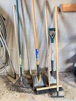 Group of long-handle garden tools leaning in garage