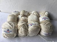 Nine of the twelve ivory yarn balls showing brand bands