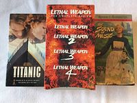 Front view of Titanic, Lethal Weapon box set, and The Sound of Music VHS covers