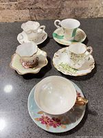 Five miniature teacups and saucers arranged on countertop