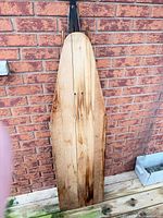 Full view of wooden ironing board leaning against wall