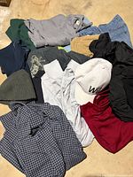 Pile overview showing multiple tops, bottoms, and hats