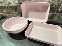 Pink enamel bowls and rectangular plates on countertop