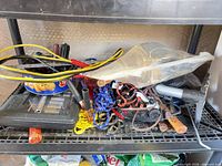 Shelf with assorted tools, cords, plastic case, tin