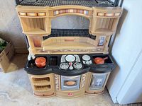 Front view of Step2 plastic play kitchen showing stove, oven door, sink and accessories