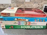 Stack of three vintage board game boxes: Scrabble Junior, Ruffhouse!, Life Doubletrack