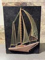 Front view showing complete sailboat string art on black velvet board
