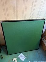 Full view of square green tabletop leaning against wall