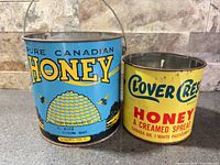 Two vintage honey tins side by side