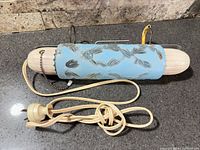 Full view of light fixture showing cord, pull chain, blue glass shade, plastic end caps