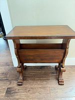 Full view of wooden side table with magazine rack and carved feet