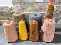 Seven assorted thread cones in two rows on countertop
