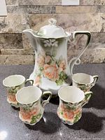 Teapot with lid and four matching cups displayed together
