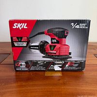 Front of sealed retail box showing SKIL 7292-02 palm sander image and features