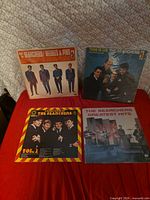 All four The Searchers vinyl LPs front covers on red surface