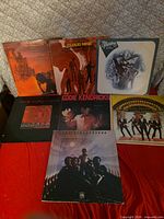 All seven album covers laid out on red surface