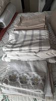 Stack of striped bedding, taupe pieces and embroidered towel