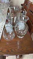 Five clear glass vases on wooden surface