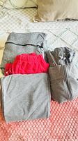 All three garments folded: grey hoodie, red sweatpants, grey sweatpants