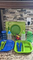 Full lot showing plates, utensils, bottles, spoon bundle