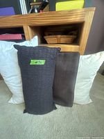 Group of three pillows: black decorative, brown lumbar, white bed pillow