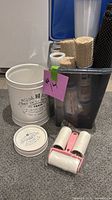 Group shot of canister, storage bin, liners, cups and lint rollers