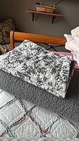 Folded black and white floral cotton quilt on bed