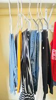 Multiple size small garments hanging: denim jeans, yellow tank, striped top, etc.