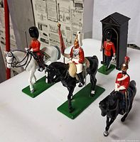 Front view of three mounted figures and standing guard
