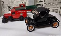 Front view of three diecast vehicles: red Canada Post van, red/green stake truck, black roadster