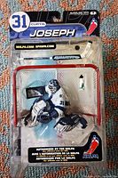 Front view of sealed McFarlane Curtis Joseph figure, accessories visible