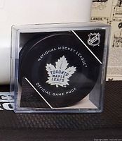 Front view of puck in case showing Toronto Maple Leafs logo and NHL markings