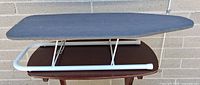 Side view of tabletop ironing board with legs extended, gray cover, white metal frame